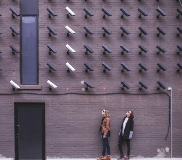 Women looking at a wall full of security cameras